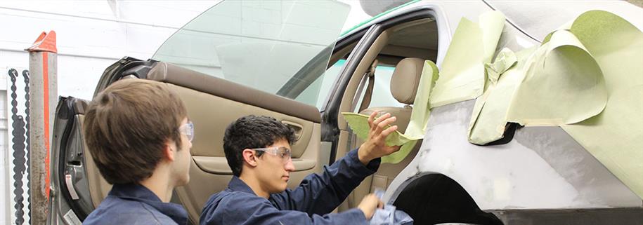 Two students work on repairing car damage